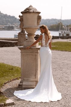 a woman in a wedding dress leaning against a fountain