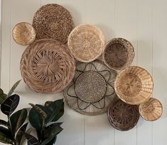 several woven baskets hanging on the wall next to a potted plant