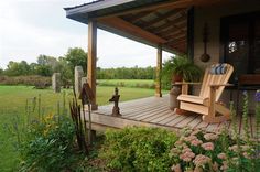 a rocking chair sitting on top of a wooden porch next to a lush green field