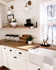 a kitchen with white cabinets and wood counter tops, two hanging lights above the sink