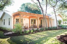 a small house with a covered patio and trees