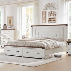 a white bed with drawers underneath it in a room next to a dresser and window