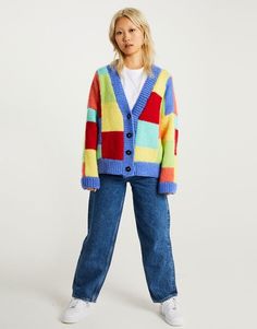 a woman wearing a multicolored cardigan sweater and jeans