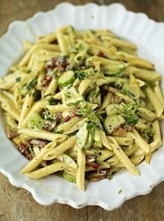 a white bowl filled with pasta and broccoli on top of a wooden table