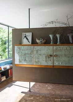 a cabinet with vases on top of it in front of a large glass window