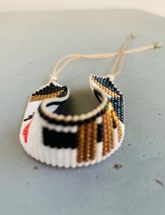 a pair of beaded bracelets hanging from strings on top of a gray surface