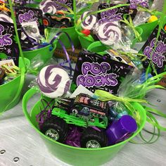 a table topped with green buckets filled with candies and candy bars covered in purple and green wrappers