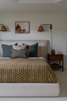 a bedroom with a bed, two lamps and pictures on the wall