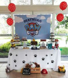 a dog themed birthday party with paw patrol decorations and food on a table in front of a large window