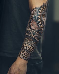 a man's arm with an intricate tattoo design on his left arm and wrist