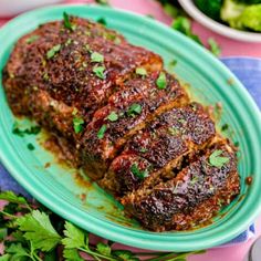 a meatloaf on a blue plate with broccoli and other foods in the background