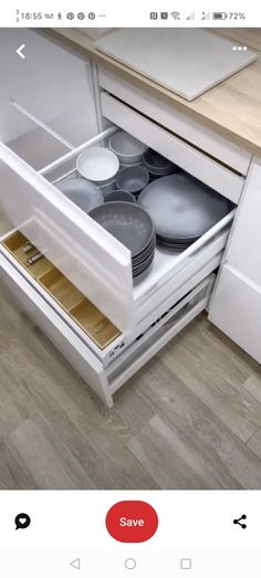 an open drawer in a kitchen with plates and pans on the bottom, next to a counter top