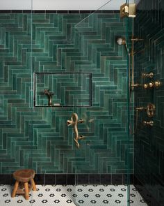 a green tiled bathroom with a wooden stool and shower faucet in the corner