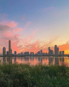 the city skyline is reflected in the water at sunset, with tall buildings on either side