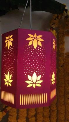 a red lamp hanging from a ceiling with yellow flowers on the top and bottom of it