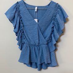 Blue Peplum Top With Surplice Neck (Snap Closure) And Ruffled Sleeve With Elastic Waist. Blue Ruffle Sleeve Tops For Vacation, Blue Flutter Sleeve Blouse For The Beach, Blue Ruffled Beach Blouse, Blue Flutter Sleeve Blouse For Vacation, Blue Ruffle Hem Top For Beach, Chic Blue Blouse With Flutter Sleeves, Blue Ruffled Blouse For Beach, Light Blue Ruffled Blouse For Beach, Blue Flutter Sleeve Tops With Ruffle Hem