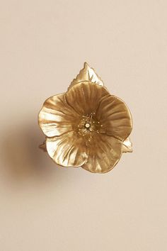 a gold flower shaped brooch sitting on top of a table next to a white wall