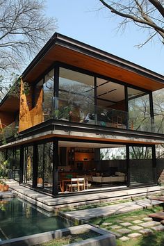 a modern house with a pool in the yard and large glass windows on the upper floor