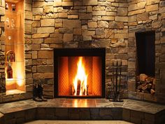 a stone fireplace with lit logs in it