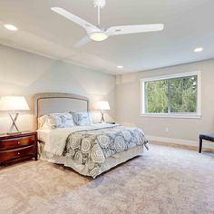 a bedroom with carpet, bed and ceiling fan