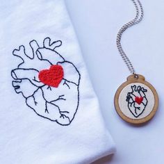 an embroidered heart on a white t - shirt next to a small wooden charm necklace