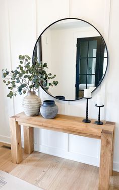 a mirror sitting on top of a wooden table next to a vase filled with flowers