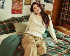 a woman sitting on top of a bed in front of a wall covered with posters