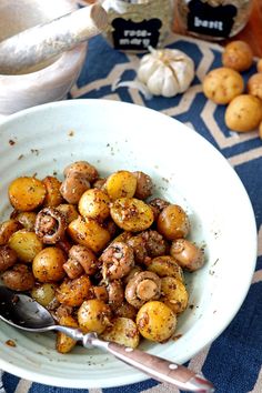 a white bowl filled with potatoes on top of a blue and white table cloth next to silverware