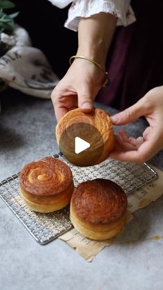 three pastries on a cooling rack being held by two hands, with another hand reaching for one