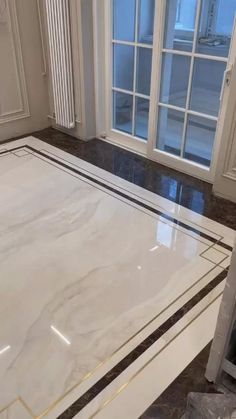 marble flooring being installed in a room with large windows and white trim on the walls