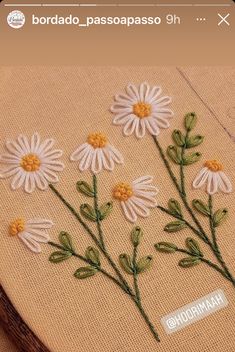 a close up of a embroidery on a piece of cloth with flowers in the middle