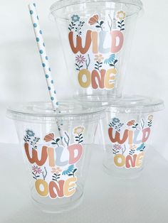 three plastic cups with different designs and straws in them on a white table top