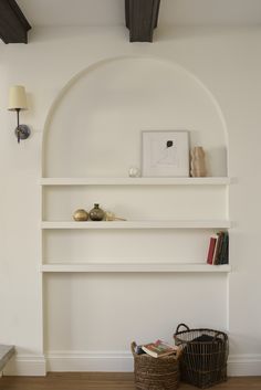 a white shelf with books and baskets on it