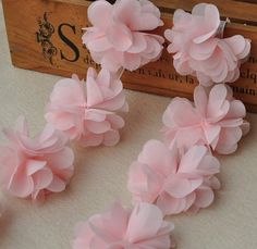 some pink flowers are sitting on a table next to a wooden box with letters and numbers