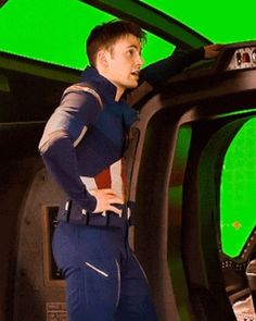 a man standing in front of a green screen with his back to the camera and hands on his hips