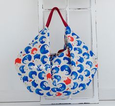 an elephant print bag hanging on a white door with red and blue handles, in front of a window