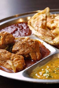 a silver plate topped with different types of food next to soup and pita bread