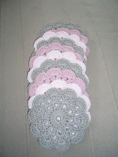 several crocheted doily are laid out on the floor, one is pink and gray