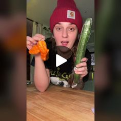 a woman holding up a cucumber and carrots in front of her face