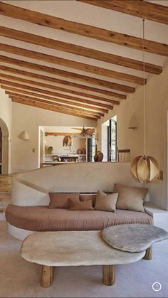 a living room filled with lots of furniture and wooden beams on the ceiling above it