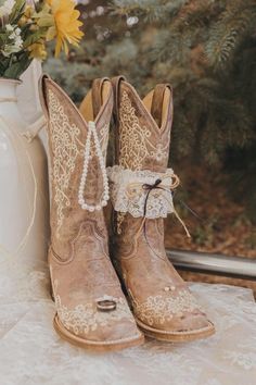 cowboy boots with lace tied to them are sitting on a table next to a vase