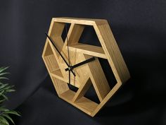 a wooden clock on a black background next to a potted plant