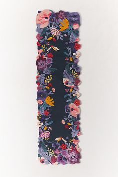 a piece of fabric with flowers and leaves on it, hanging from the wall in front of a white background