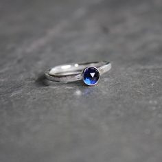 Do you need a gift for someone with a September birthday or to celebrate your 5th wedding anniversary? This sterling silver synthetic sapphire stacking ring is perfect if your birthstone is sapphire or you need a simple navy blue ring. Here are the details:This ring is made with either a rose cut (faceted) or smooth 5mm synthetic sapphire cabochon set in a sterling silver bezel and on a sturdy band handmade in your size. It can be worn with other stackable rings, or by itself.Please select your Anniversary Sapphire Stackable Rings, Anniversary Sterling Silver Birthstone Ring With Tension Setting, Modern Anniversary Birthstone Ring With Round Stone, Anniversary White Gold Stackable Sapphire Ring, Round Cut Sapphire Stackable Rings For Promise, Stackable Round Sapphire Ring For Anniversary, Modern Sapphire Ring With Tension Setting As A Gift, Sapphire Stackable Rings With Gemstone, Dainty Stackable Sapphire Birthstone Rings