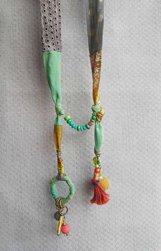 a necklace with beads and tassels hanging from it's side on a white surface