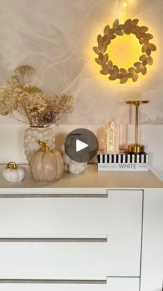 a white dresser topped with lots of vases and decor on top of it's drawers