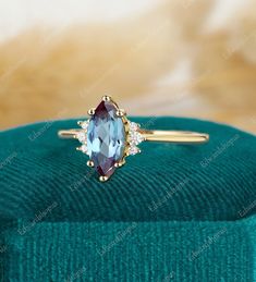 a ring with an oval cut blue topazte surrounded by small white diamonds on a green velvet box