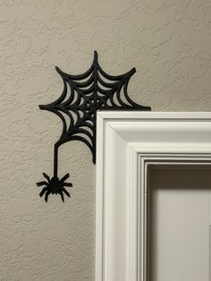 a spider web hanging on the wall next to a white framed frame with an open door