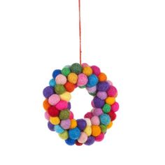 a multicolored felt wreath hanging from a string on a white background with a red cord