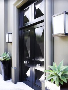 a black front door with two planters on the side and one potted plant next to it